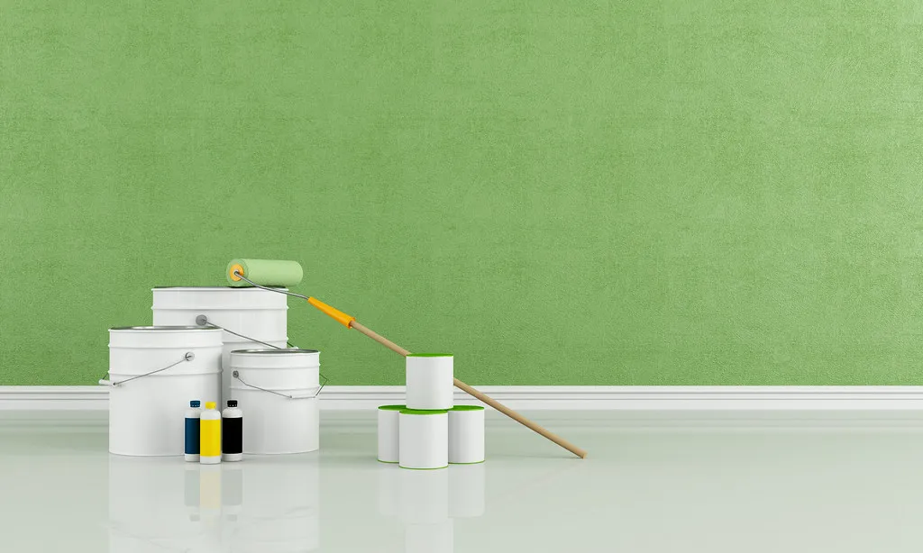 Mur fraîchement repeint en vert, pots de peinture et rouleau au sol